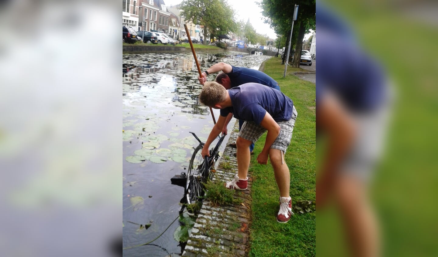 De foto van Henny Ottenhof: mannen vissen hun fietsen uit het water 