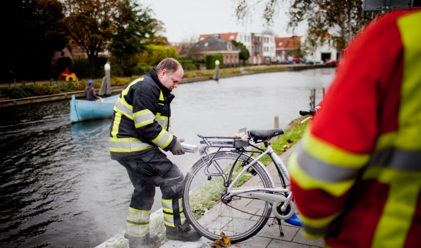 Brandweerman haalt beschadigde accu uit fiets.