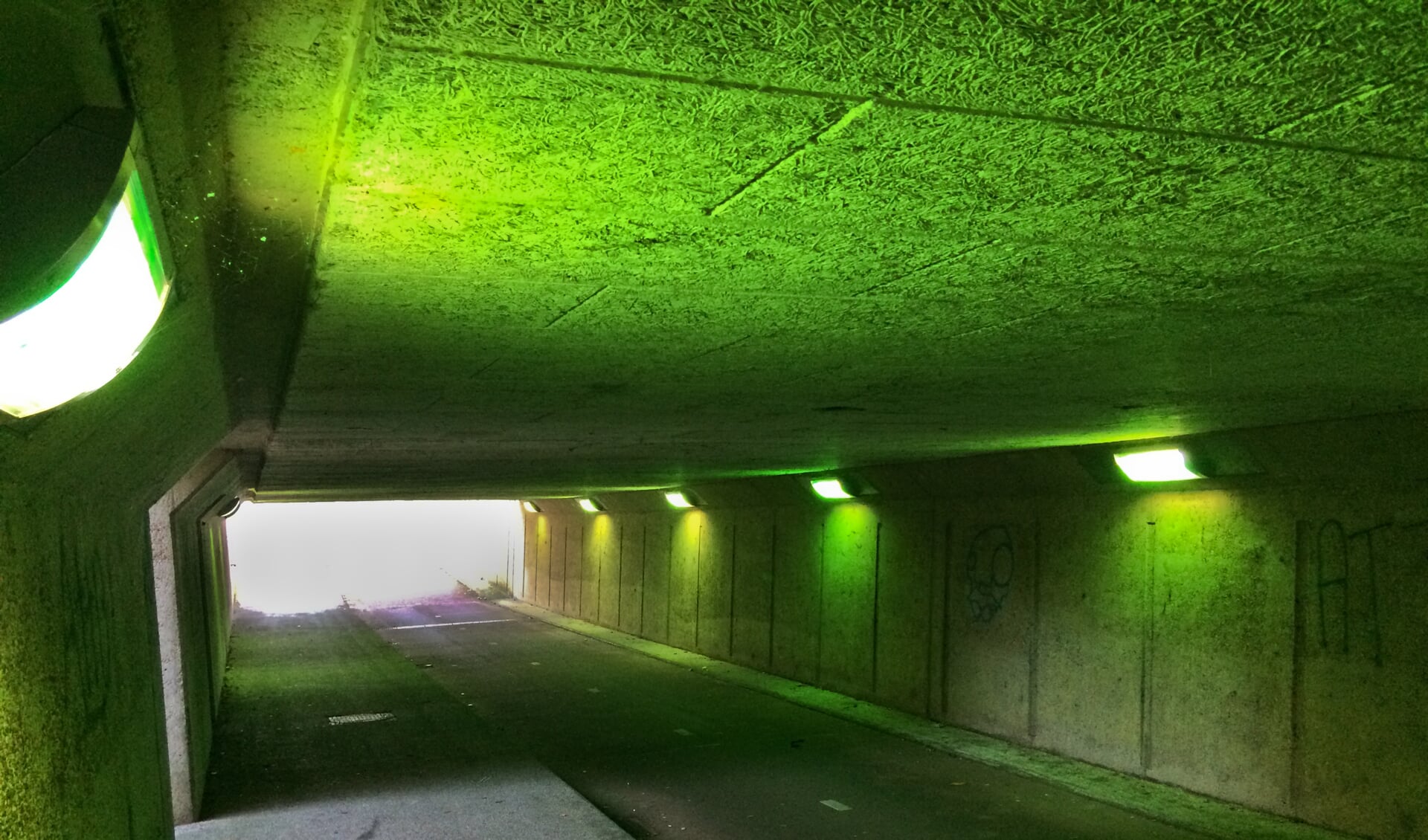 De tunnel is ineens groen door de grafitti. 