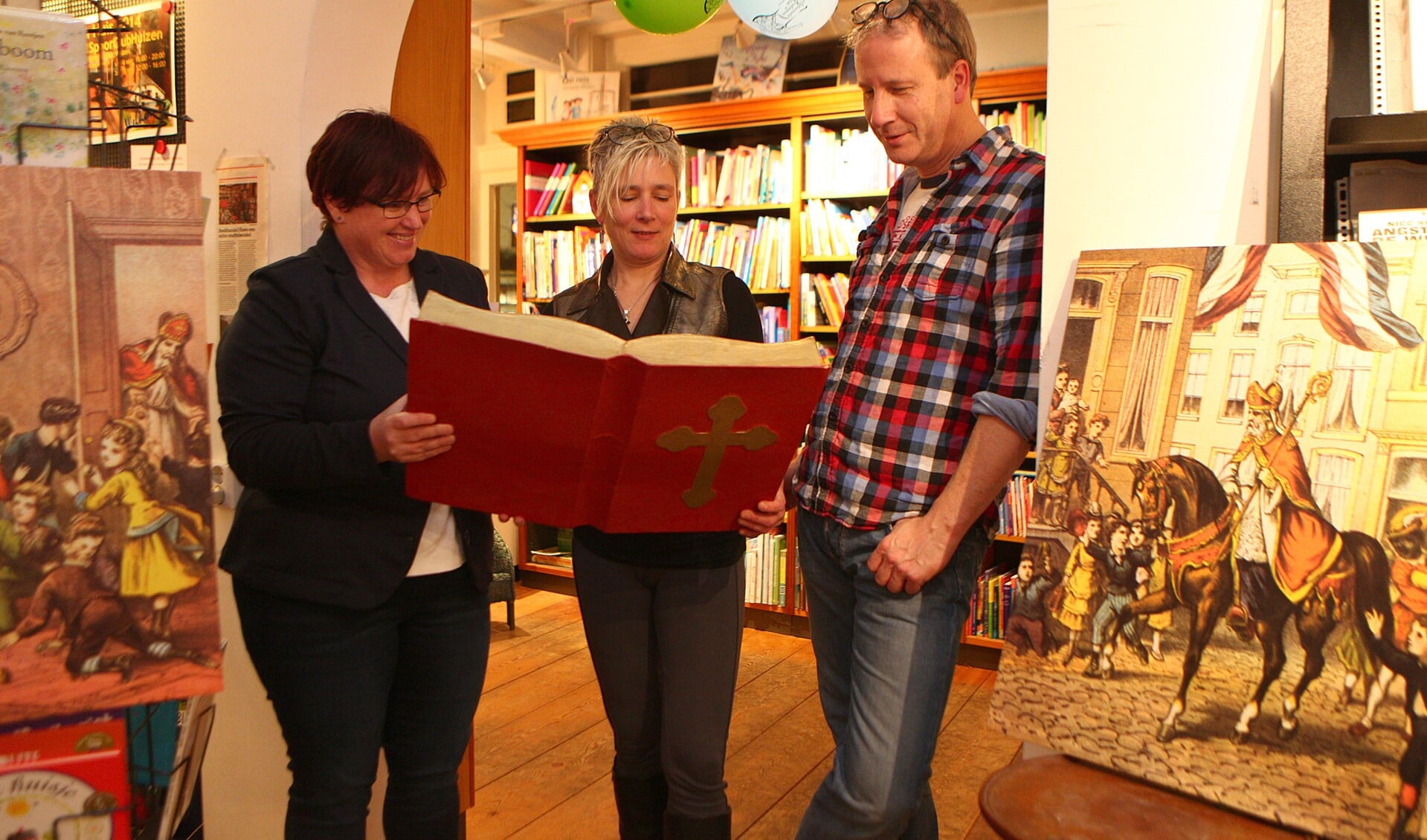 Carin (links) bestudeert alvast samen met Marieke en Luud van Boekhandel Flevo het grote boek van Sinterklaas.
