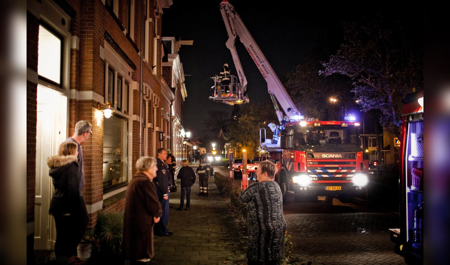 Buurtbewoners staan buiten naar de brandweer te kijken.