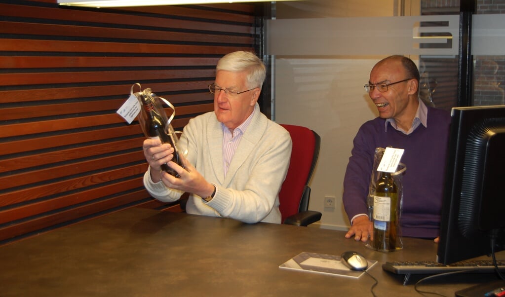 Jaap Bos (links) en Glenn Marcet worden verrast met een fles wijn.  