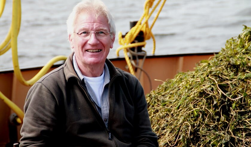 Vrijwilliger Jan Molenaar op de tot maaiboot omgebouwde vissersboot.
