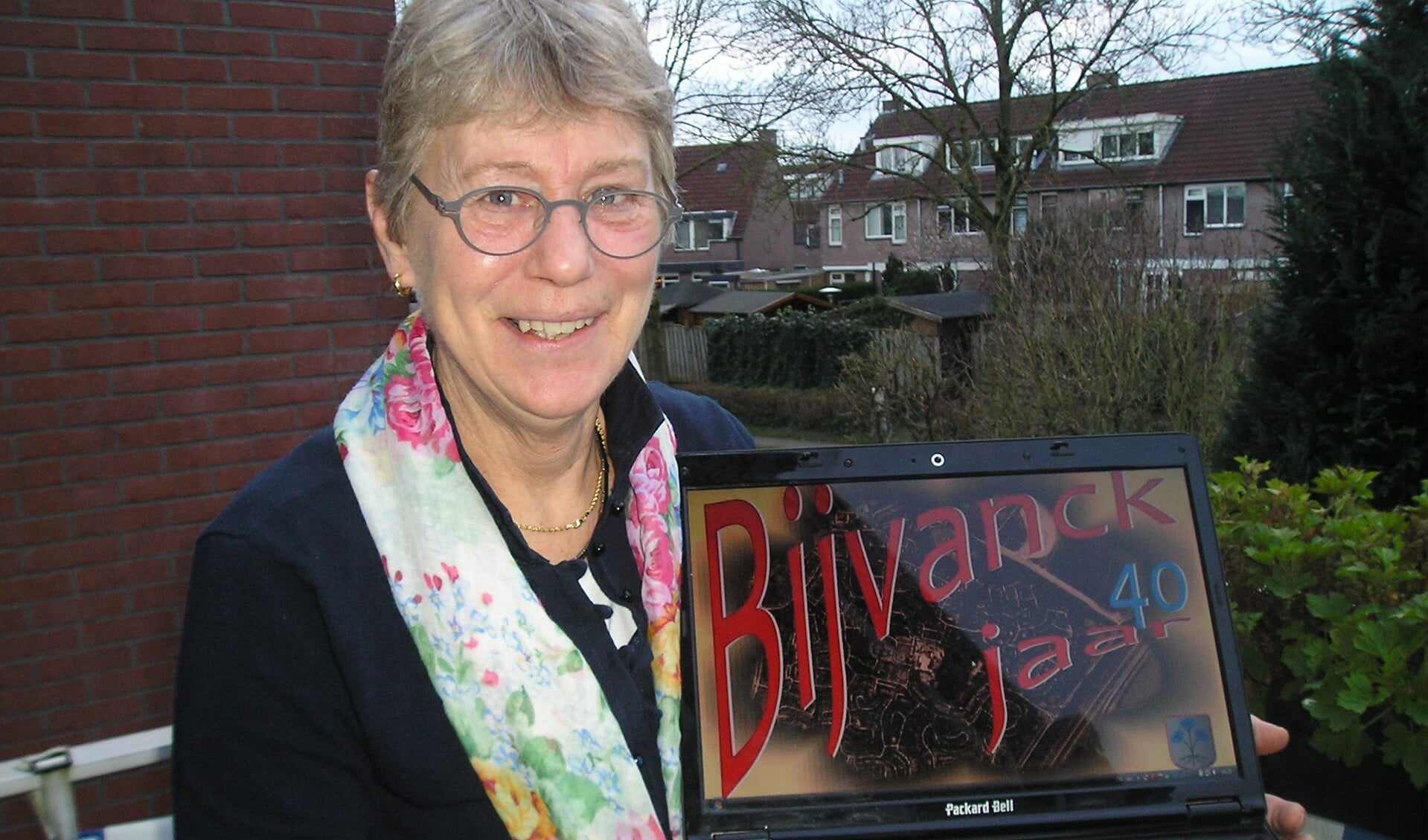 Jetty van Hoven toont het logo van Bijvanck 40 jaar; een kaart van de wijk vormt de achtergrond hiervan.