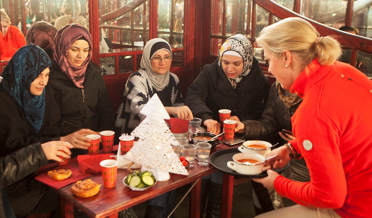 Van links naar rechts: moeder Raha met dochter Doe, Ghada en Fayza - allen vluchtelingen uit Syrië - en een vrijwilliger die soep aanbiedt.