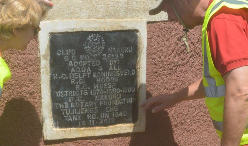 Annemarie Worm en Marten Snijder lezen een Rotary-plaquette op een watertank in Kenia.