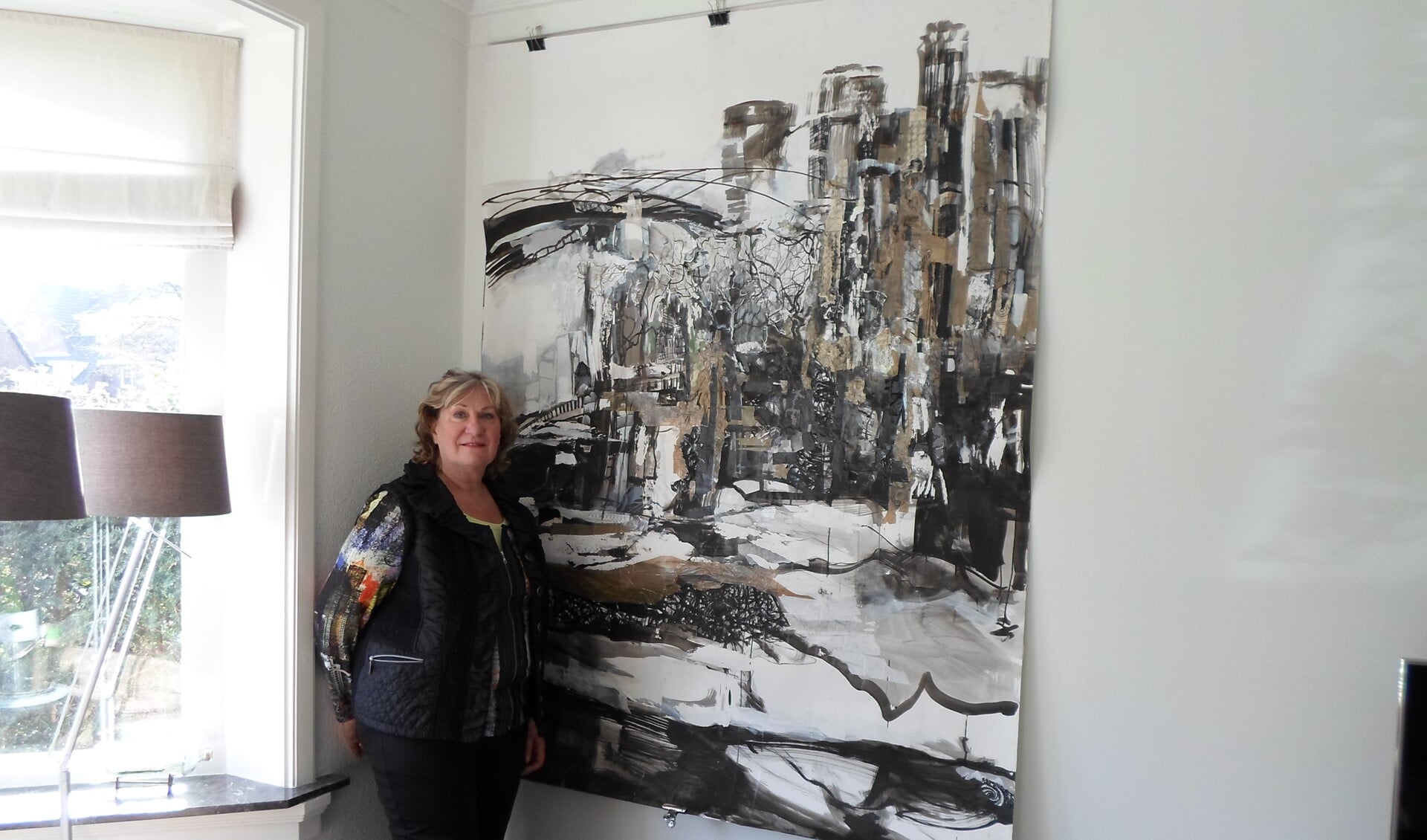 Kunstenares Iris van Keulen bij het doek dat nu nog in de hoek van haar woonkamer hangt en straks in het Gemeentemuseum in Den Haag.
