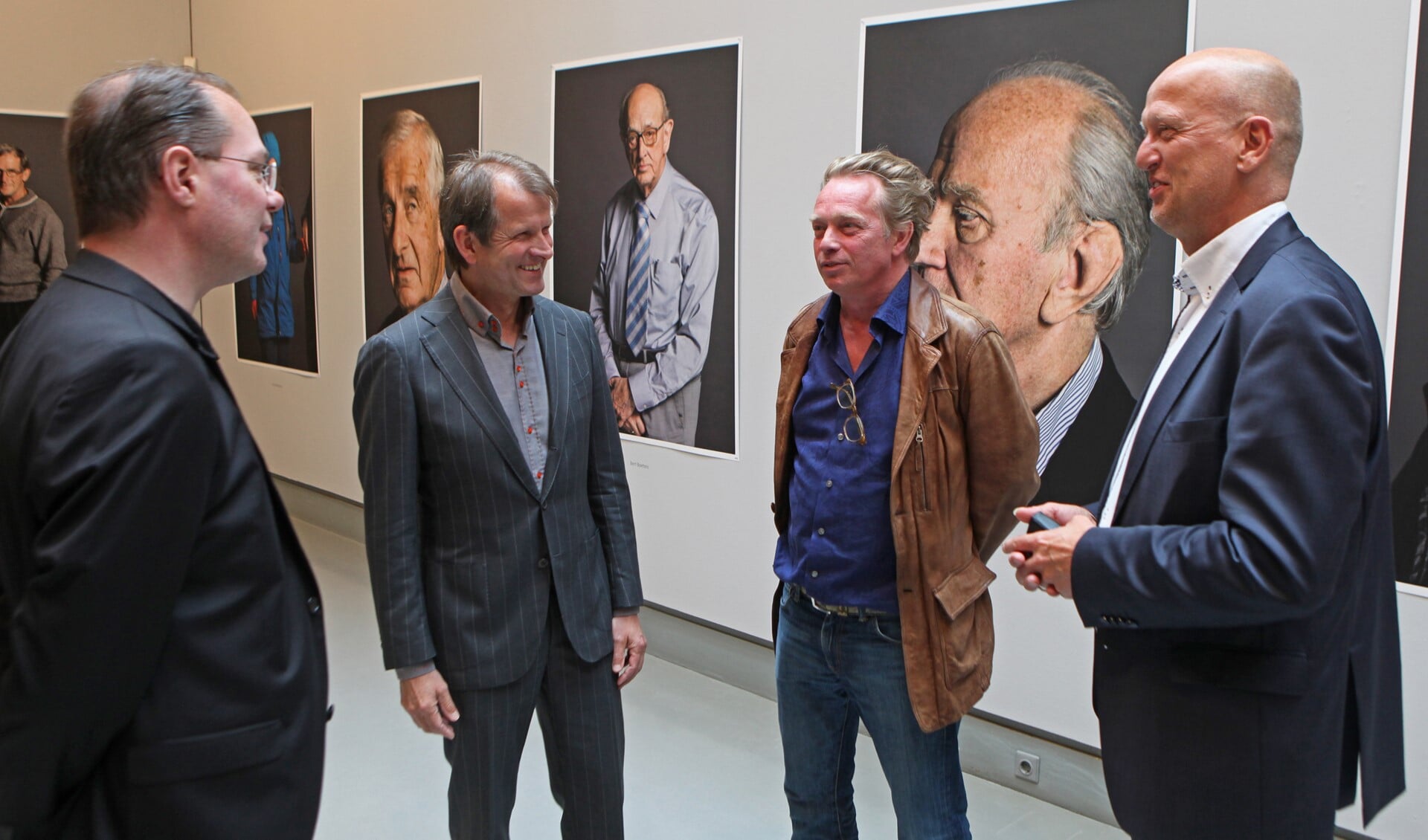 Koos Breukel (tweede van rechts) tussen zijn opdrachtgevers op de expositie met zijn portretten van Erfgooiers.