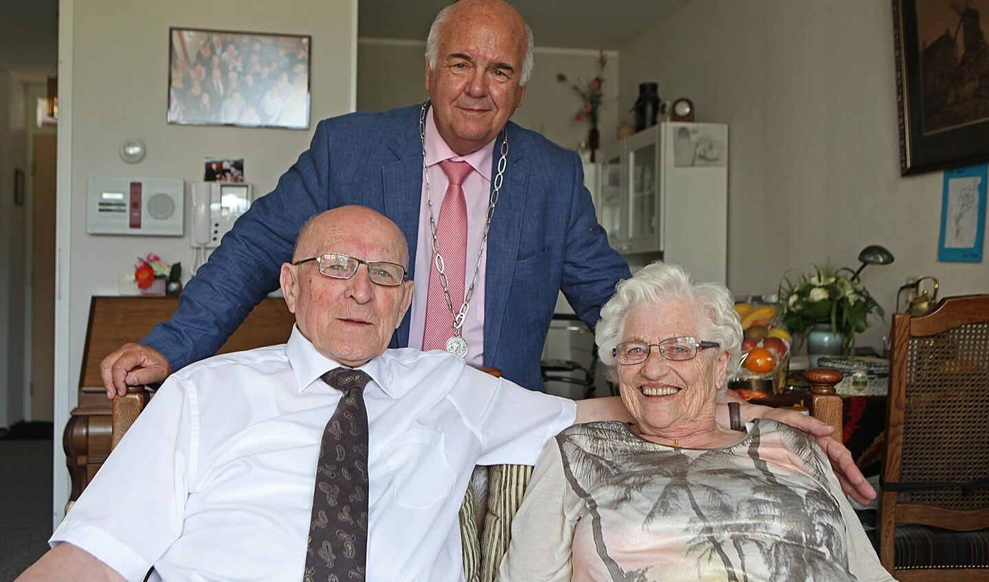 Jan en Henny op de bank met daarachter de burgemeester.