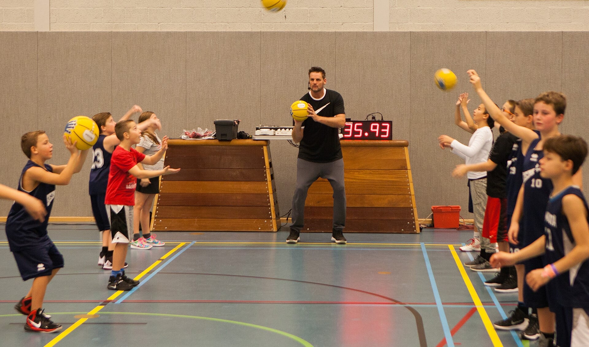 Oud-prof Henk Pieterse brengt de kinderen de fijne kneepjes van het basketballen bij.