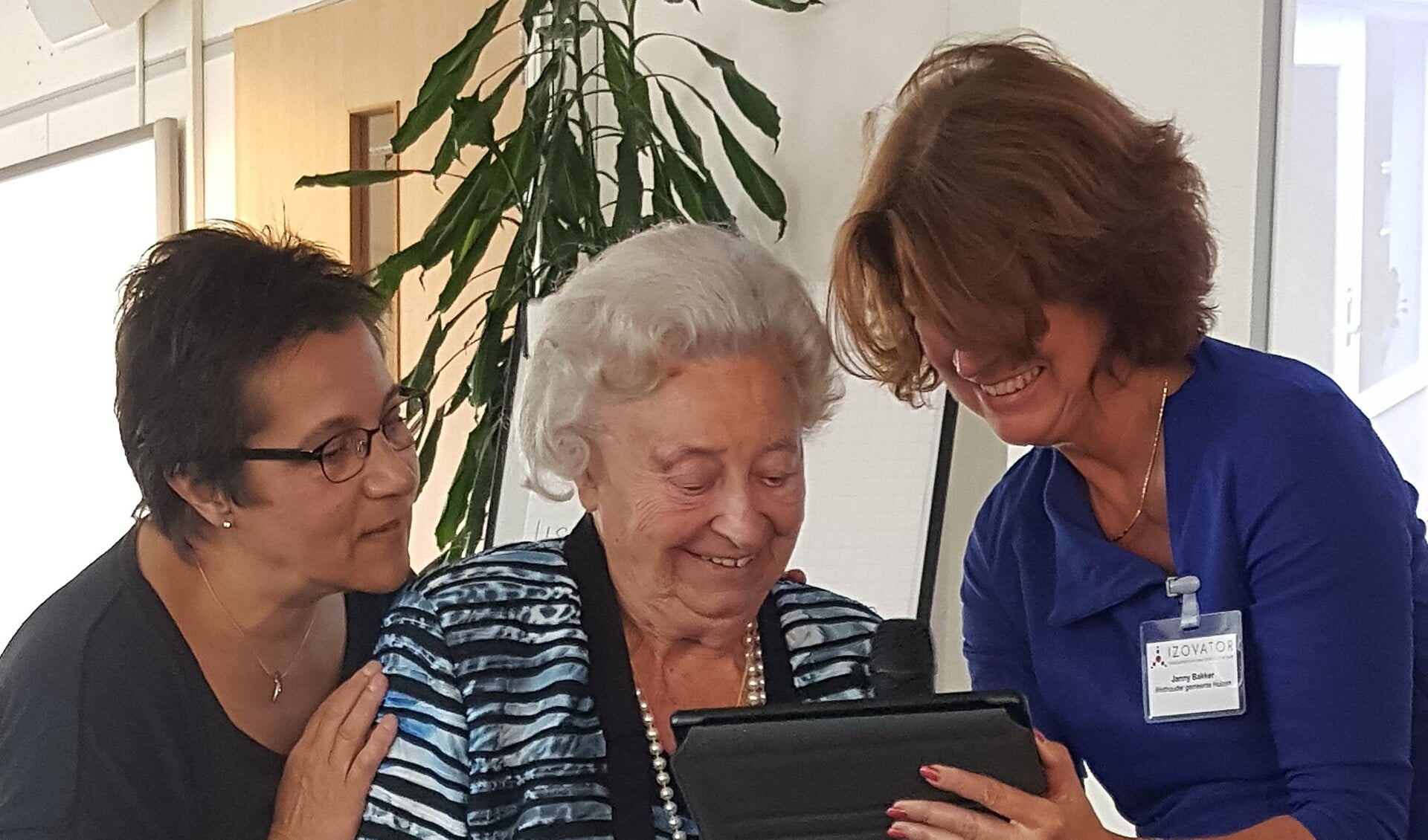 Wethouder Janny Bakker toont mevrouw Brouwer de tablet met Dementia-app.