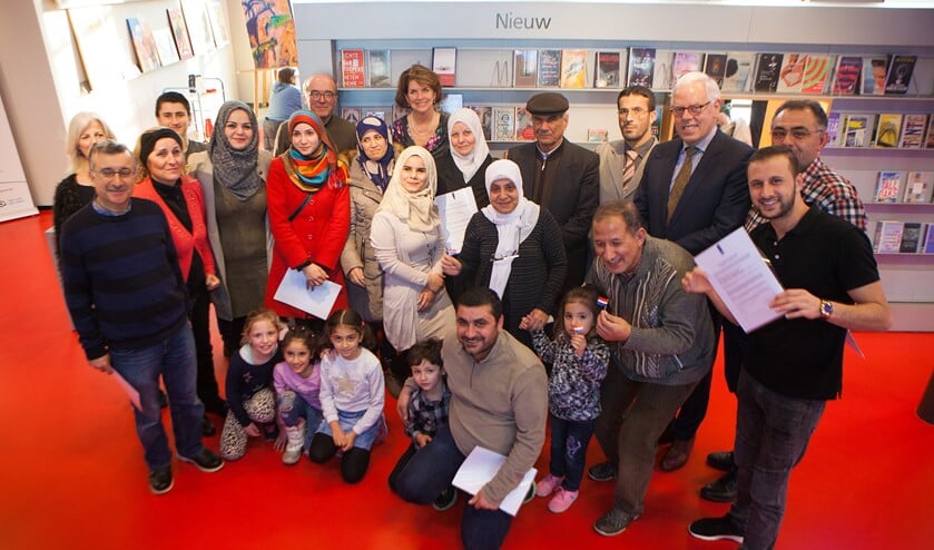 De statushouders, met in het midden in het crème gekleed de 19-jarige Malak, de wethouders uit Huizen en Laren en medewerkers van het Taalcafé.