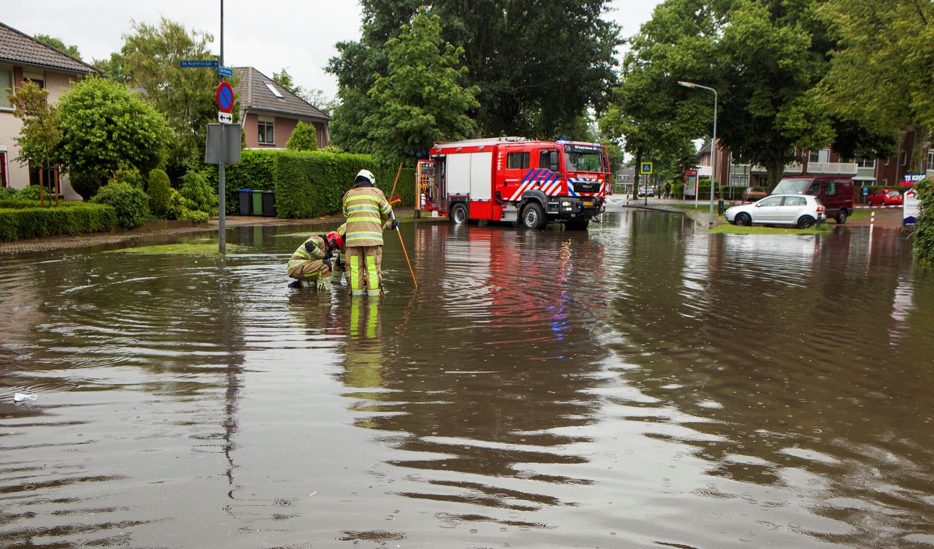 De brandweer maakt de grote straatputten open om het water sneller weg te laten lopen.