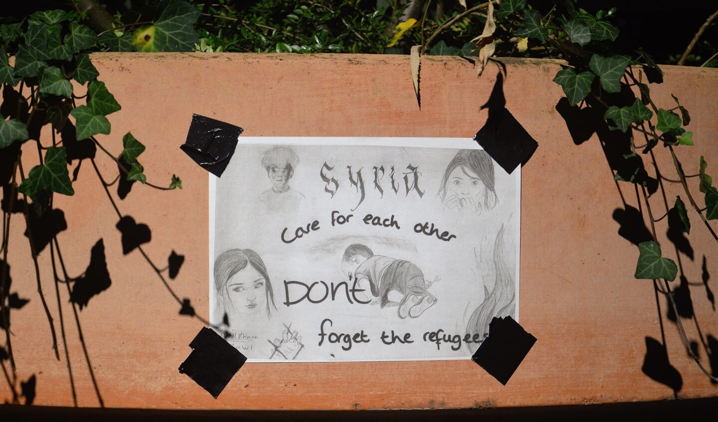 De poster met de tekst 'Care for each other, don't forget the refugees', ontworpen door een jongen in Syrië.