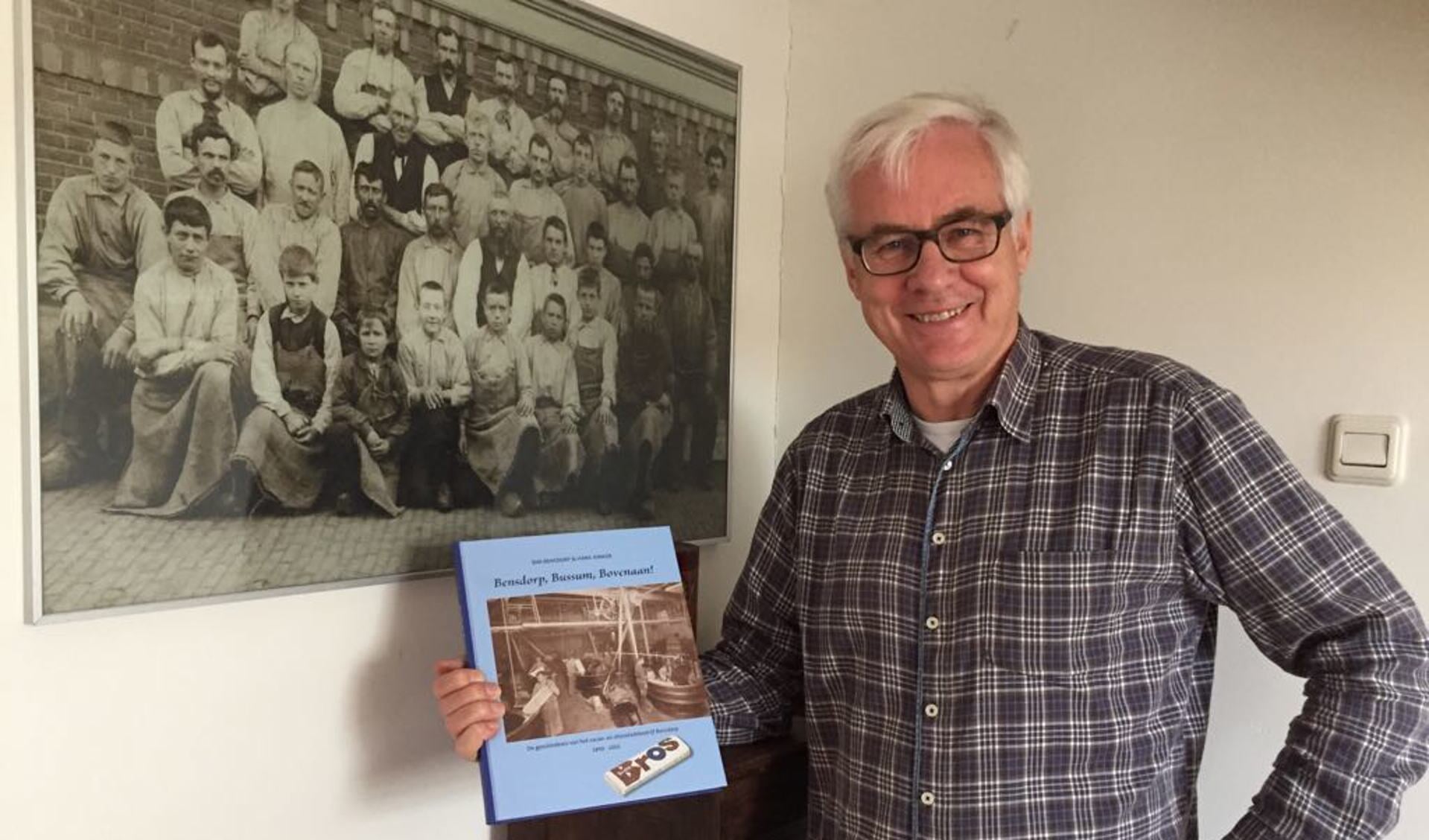 Hans Jonker met het boek bij een foto van werknemers van Bensdorp in vroegere tijden.