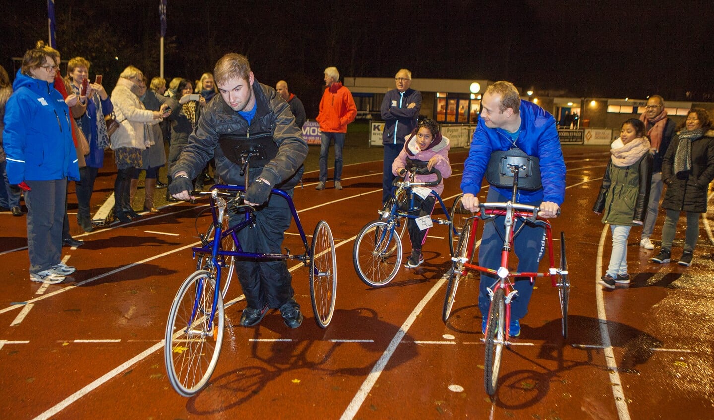 Jan, Noa en Sander geven een demonstratie racerunning bij Atletiekvereniging Zuidwal. Trainer Cees Leeflang kijkt er achter met gekruiste armen toe.