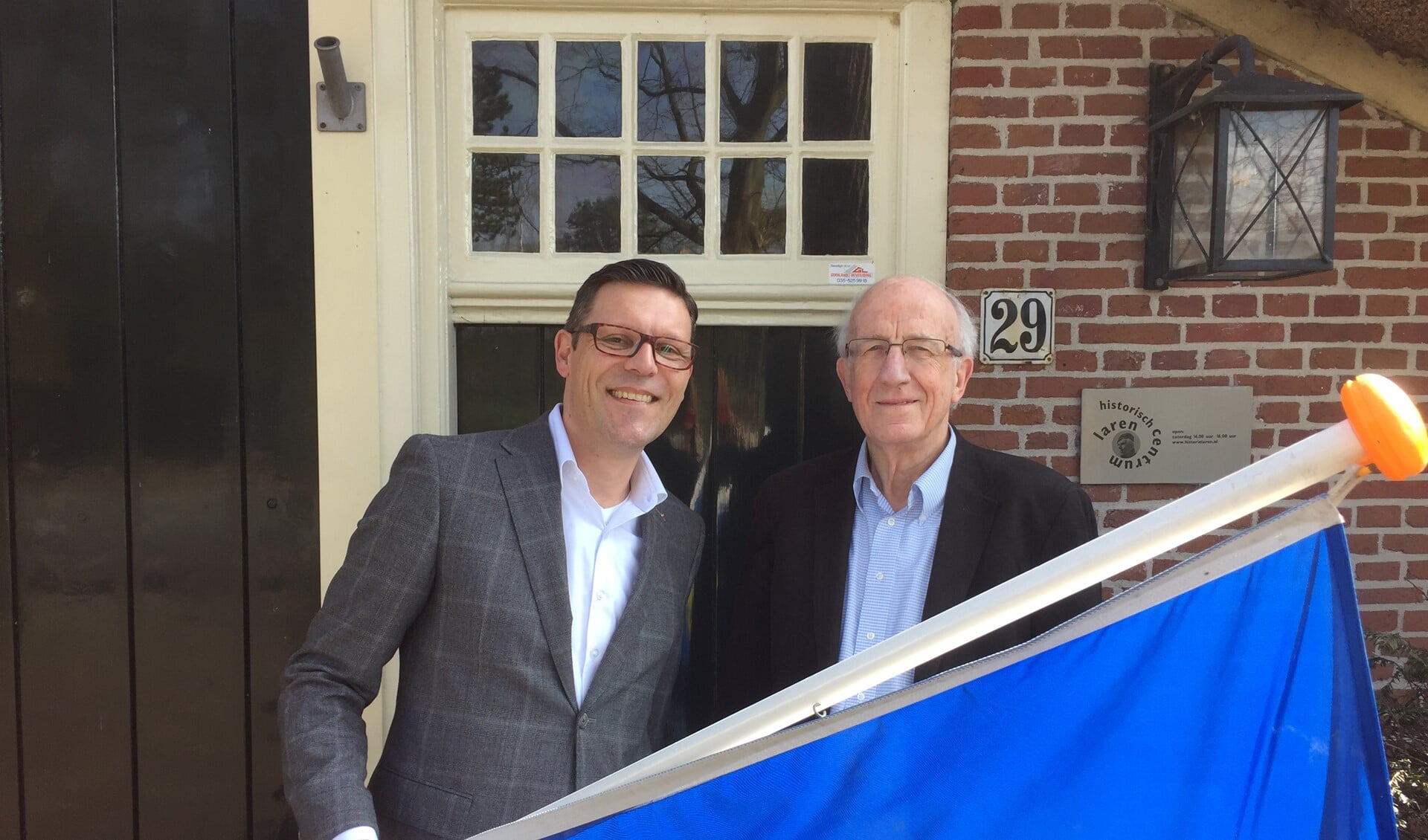De nieuwe voorzitter Bas Holshuijsen samen met penningmeester Jos Joosen voor de Lindenhoeve met de Larense vlag.