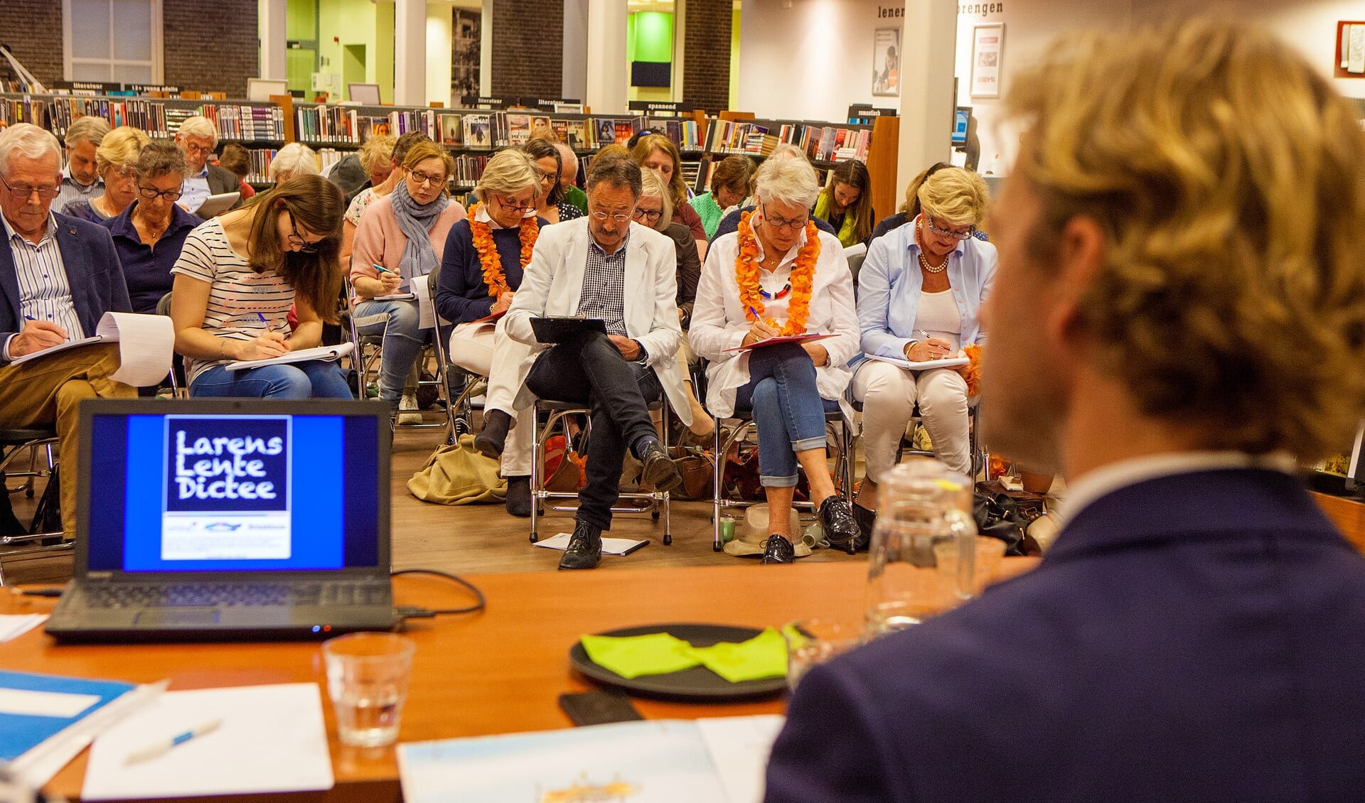 Juryvoorzitter Tijmen Smit kijkt toe hoe de deelnemers aan het schrijven zijn.