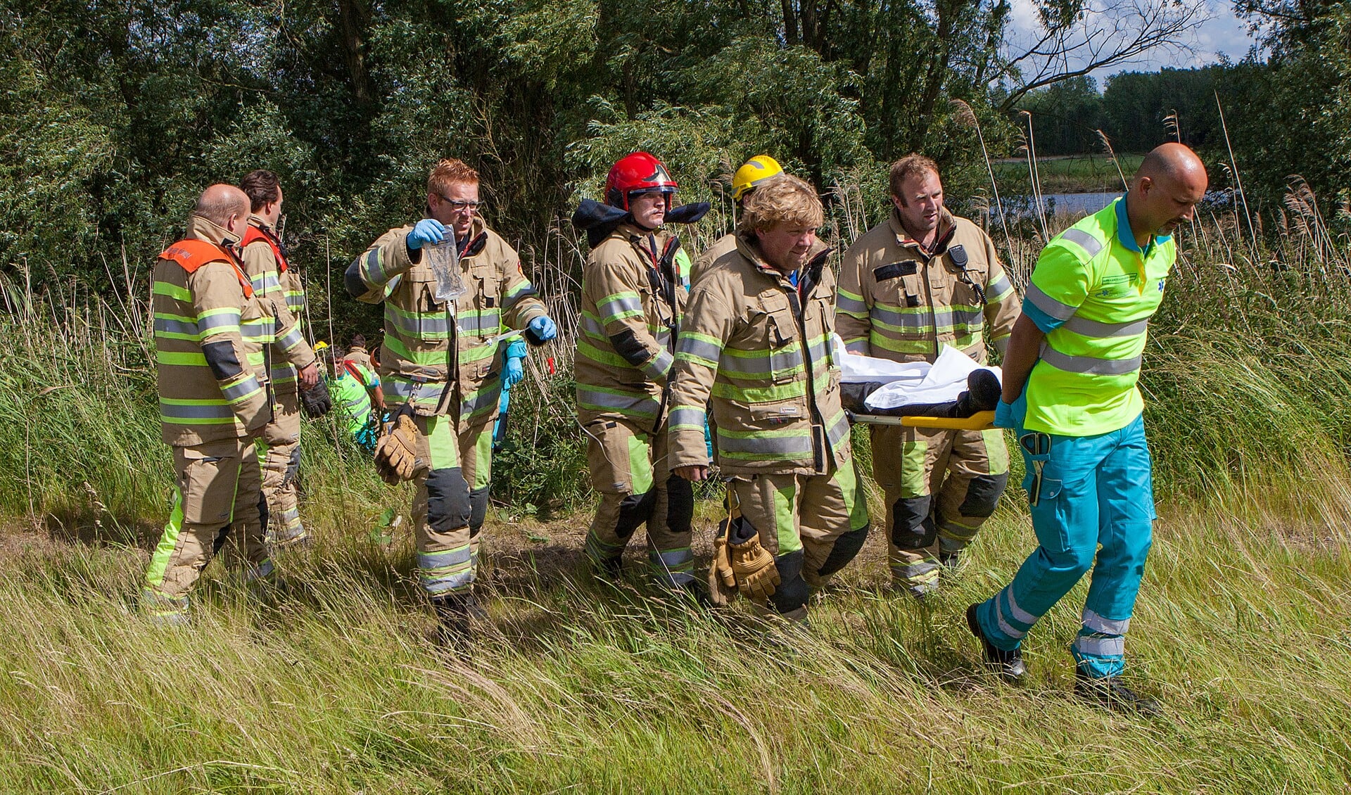 De brandweer droeg het slachtoffer het talud op naar de ambulance.