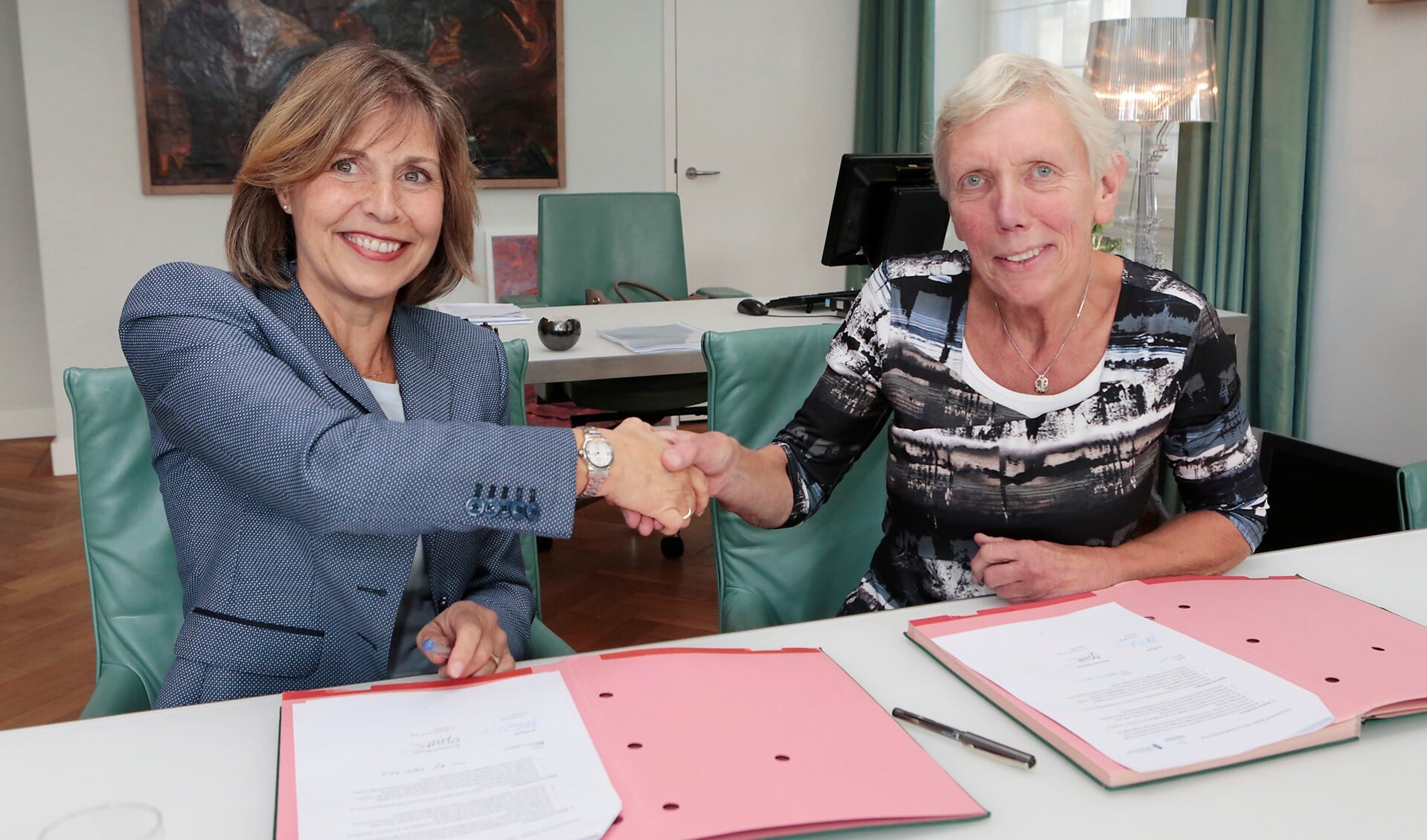 Joan van der Burgt (directeur van de Alliantie) en wethouder Liesbeth Boersen (r) schudden elkaar de hand na het ondertekenen van de overeenkomst.