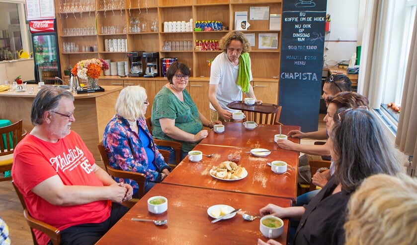 Mark serveert zijn zelfgemaakte soep. Linksachter aan tafel in het groen gastvrouw Anneke.