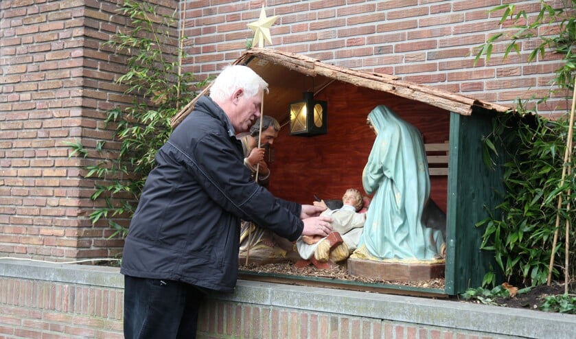 Kees Kuijpers rangschikt de buitenkerststal van de Weesper parochie.