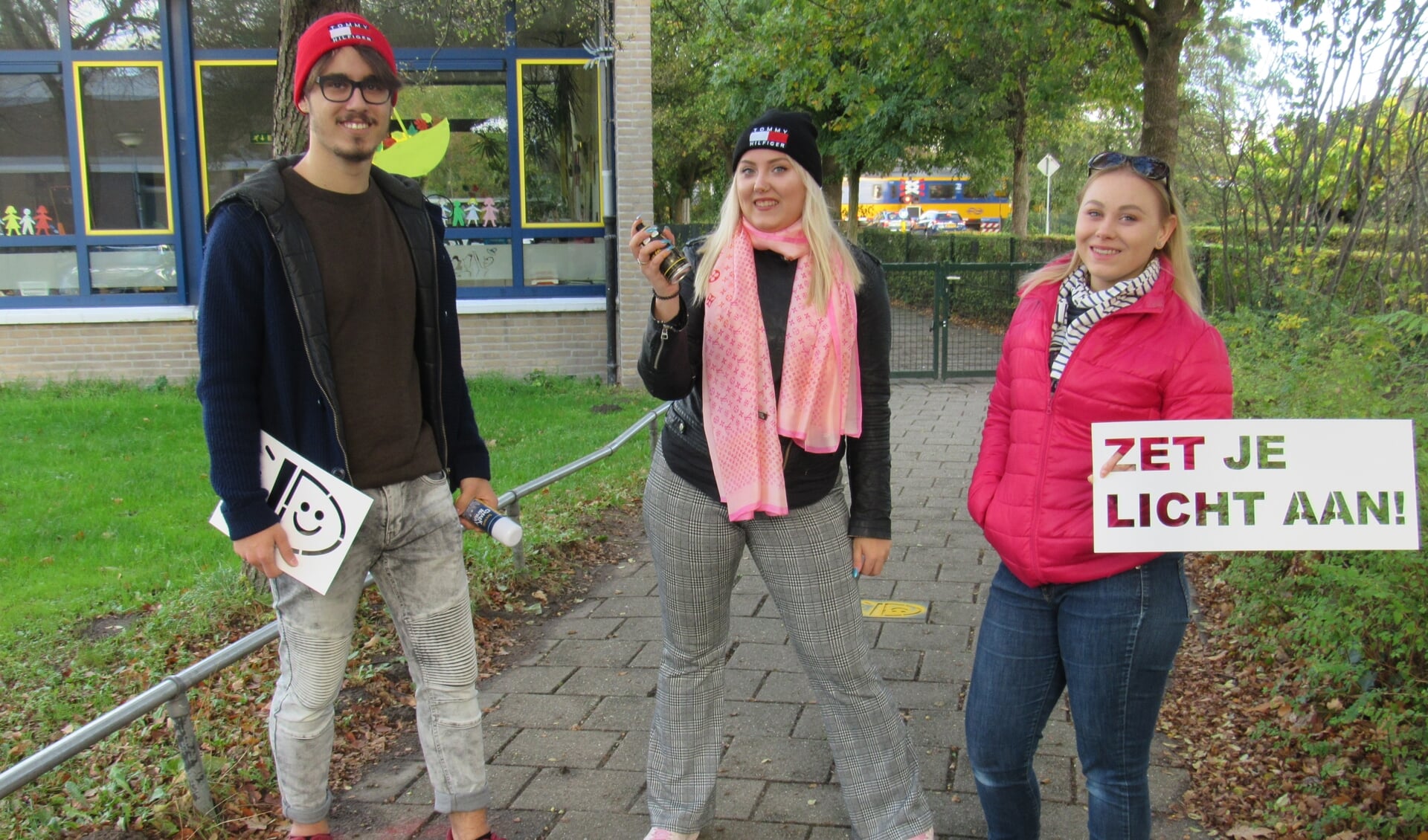 Mees, Else-Meike en Willemijn spoten met spuitkrijt de tekst 'Zet je licht aan' op fietspaden rond scholen. 