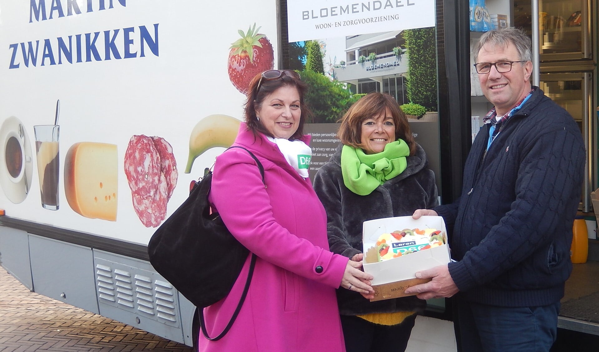 Statenlid Claudia Weemhoff (l) en Ellen van Brakel van D66 Laren overhandigen de taart van Martin Zwanikken. 