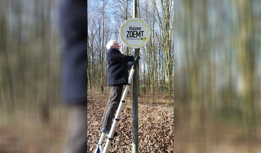 Wethouder Gerrit Pas bevestigt het bord dat laat zien dat Huizen bijvriendelijk is.