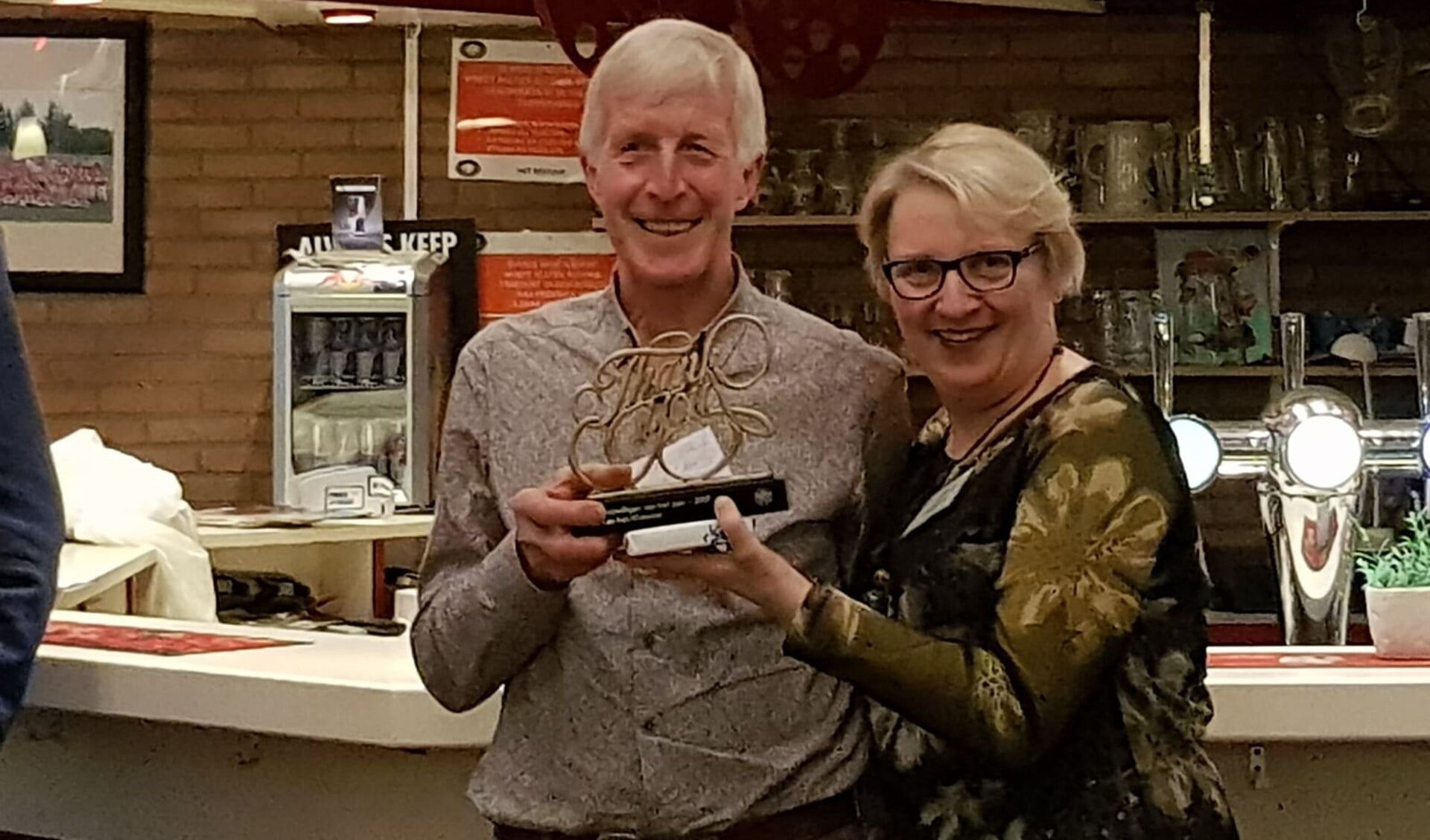 Piet van 't Klooster krijgt uit handen van sportwethouder Marianne Verhage de trofee die hoort bij Sportvrijwilliger van het Jaar.