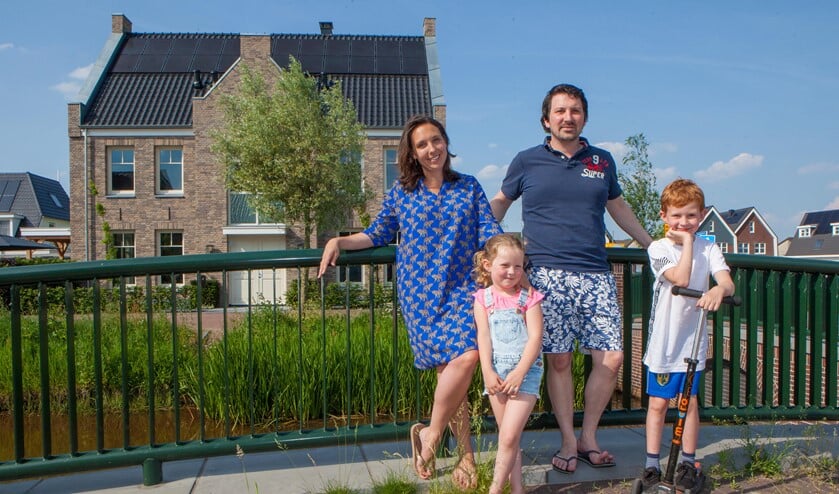 Saskia en Justin en hun kinderen in de Zuidpolder. Op de achtergrond hun nieuwe woning.