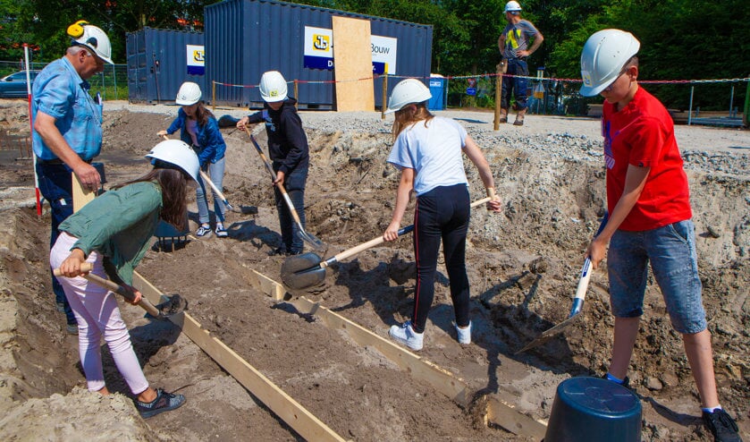 Leerlingen helpen bij het leggen van het fundament van de school.
