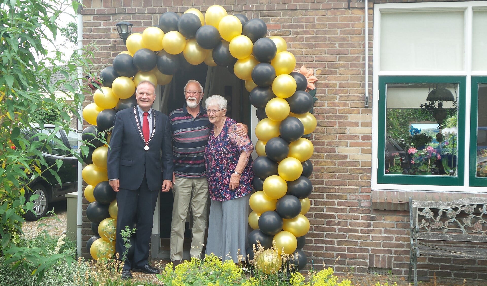 Het echtpaar Klijn-Kuit met de burgemeester voor de versierde voordeur.