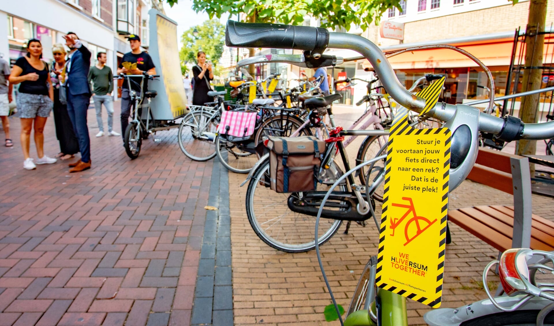 Geel-zwarte hangers op verkeerd geparkeerde fietsen. Nu is het nog waarschuwen geblazen.