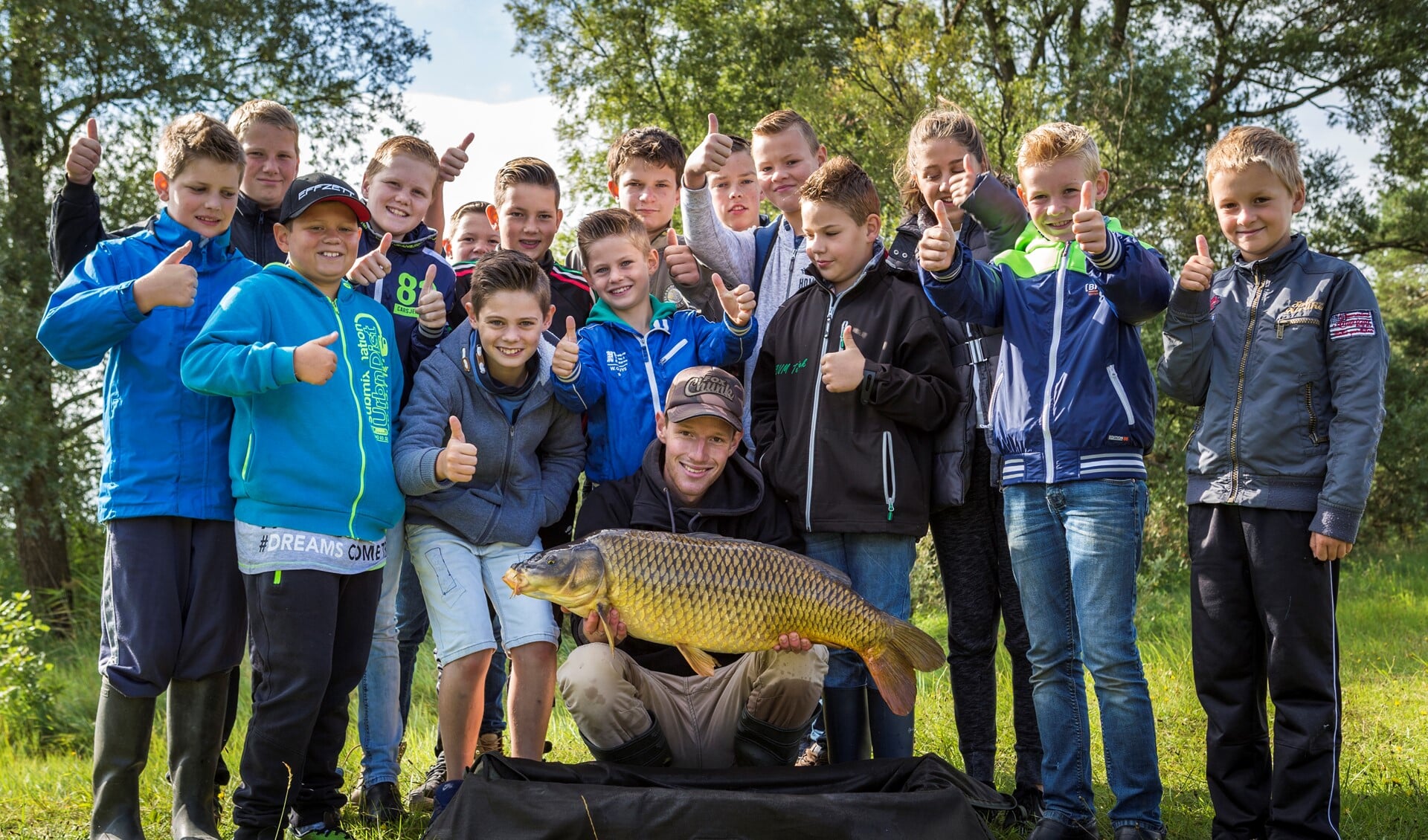 Jongelui tonen trots de vis die zij hebben gevangen tijdens een jeugdVISdag.