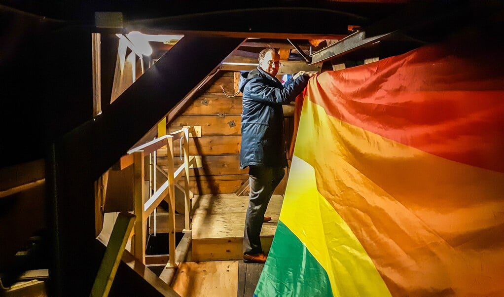 Wethouder Léon de Lange vanmorgen vroeg op de zolder van het stadhuis, waar hij de grote regenboogvlag hijst.