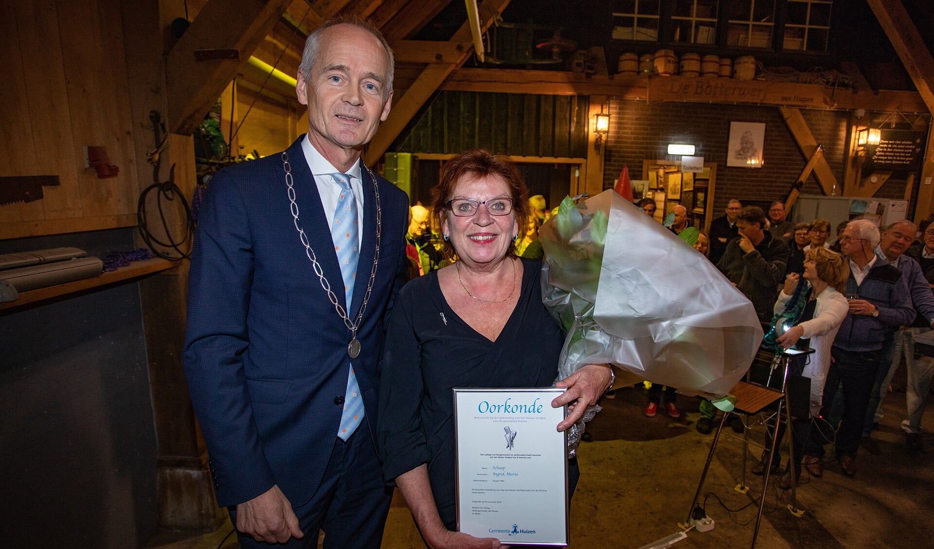 Burgemeester Niek Meijer met Ingrid Helmus-Schaap die het Huizer Insigne van hem kreeg opgespeld.