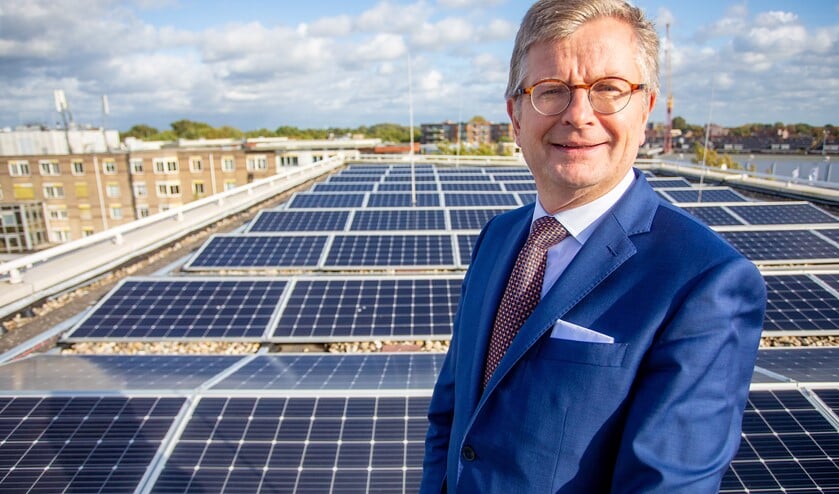 Wethouder Bert Rebel van duurzaamheid bij de zonnepanelen op het dak van het gemeentehuis, waar een straffe wind stond.