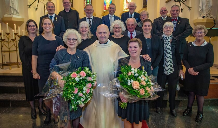 Bloemen en onderscheidingen voor twee koorleden.