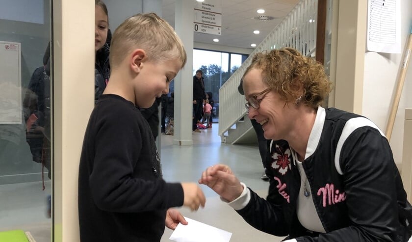 Levi geeft zijn kaartje aan juf Ied. Sam (op de achtergrond) heeft een kaartje voor juf Britt bij zich.