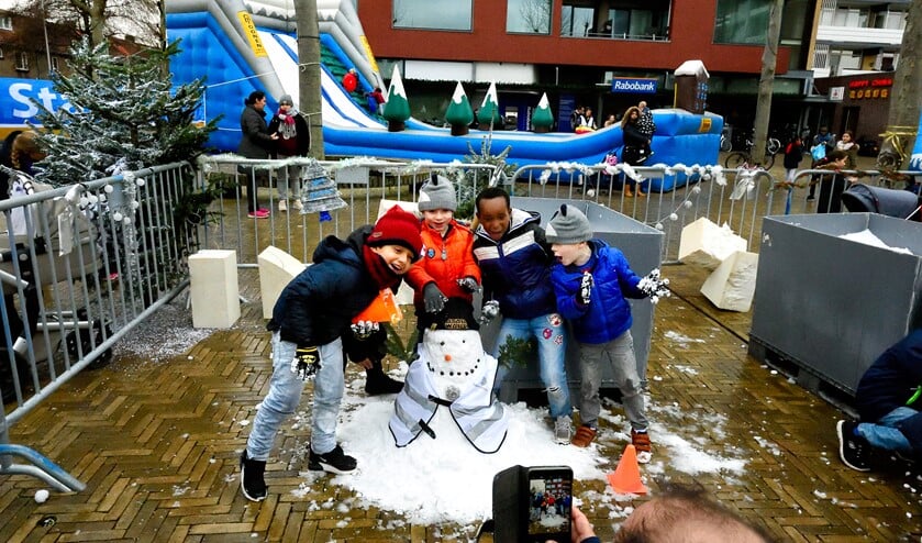 Kinderen tonen trots hun sneeuwpop.