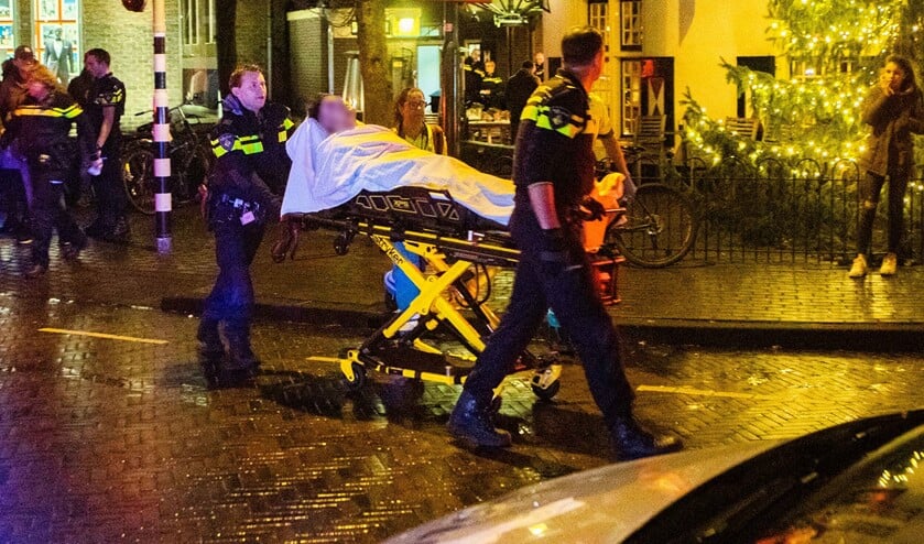 De gewonde agent wordt door collega's naar de ambulance gereden.