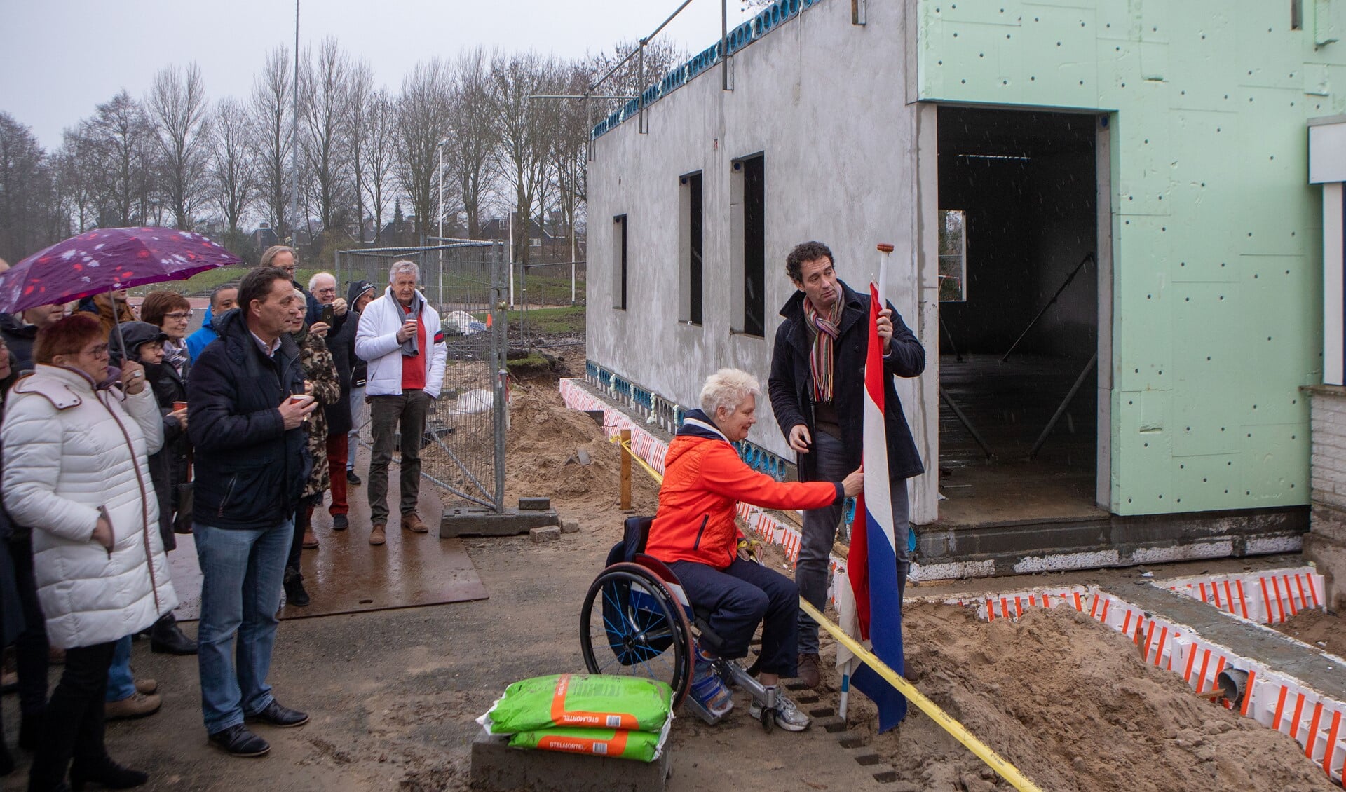 Wethouder Roland Boom en atleet Djoke van Marum staan klaar om de vlag te hijsen om het hoogste punt van de nieuwbouw te vieren.