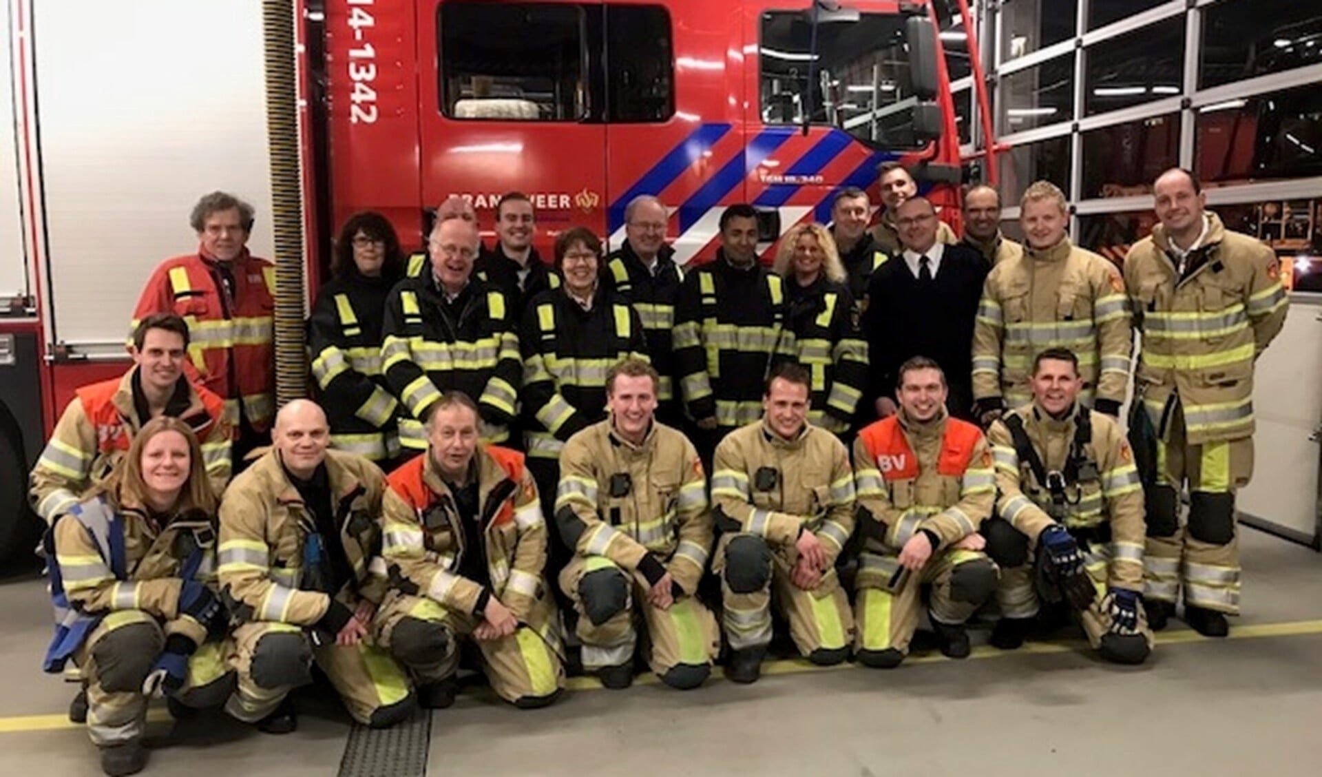 De brandweerlieden samen met de raadsleden (veelal in het donkere brandweerpak) op de foto.