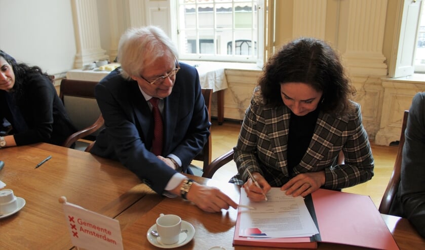Burgemeester Bas Jan van Bochove van Weesp wijst zijn Amsterdamse collega Femke Halsema waar zij moet tekenen om de ambtelijke fusie. Inmiddels worden de laatste stappen gezet van de daadwerkelijke fusie in 2022.