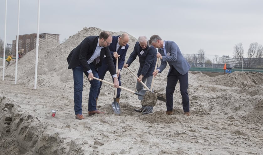 Wethouder Leon de Lange (links) helpt bij het begraven van een tijdcapsule.