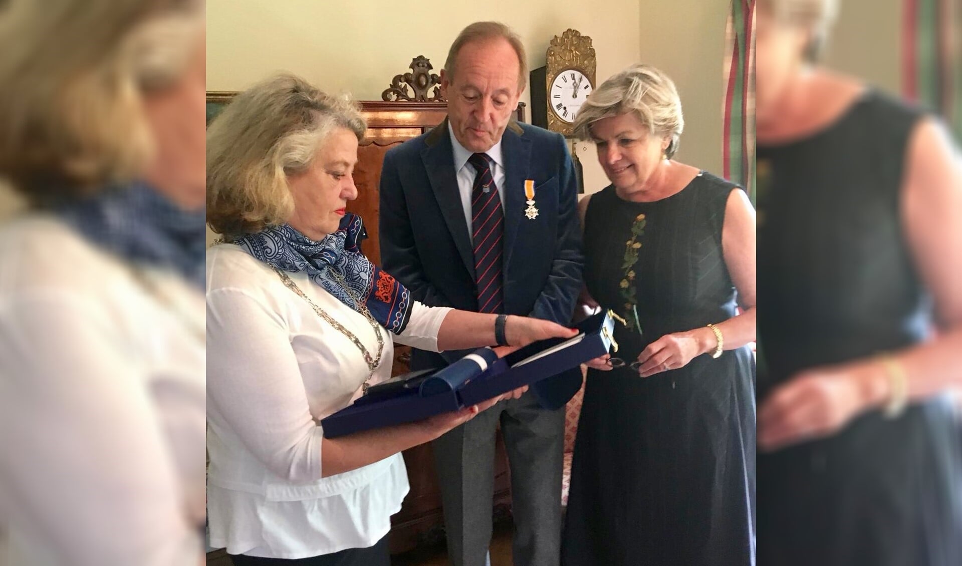 De burgemeester toont het echtpaar Van den Brink alle toebehoren bij de onderscheiding.