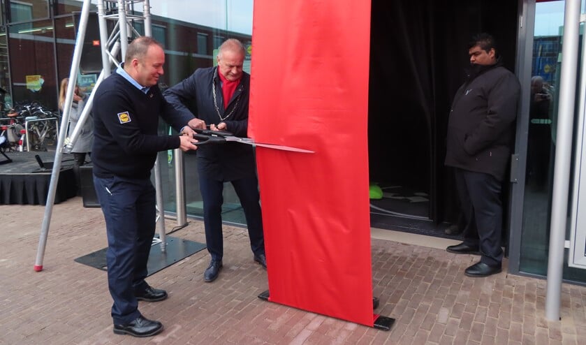 Burgemeester Sicko Heldoorn en supermarktmanager Jack knippen het lint door.