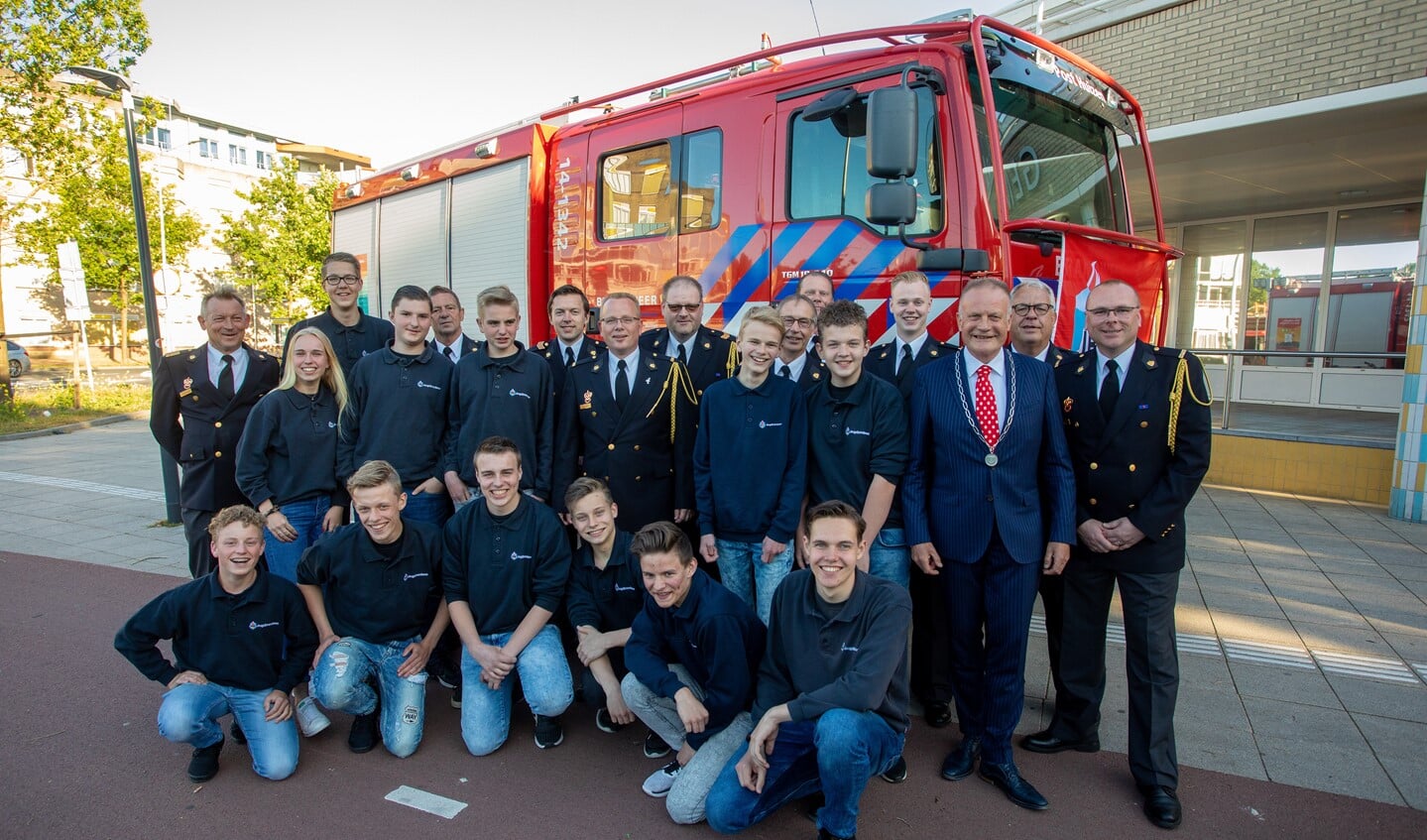 De jeugdbrandweer met begeleiding met links brandweercommandant John van der Zwan en rechts postcoördinator Fred Kos, geflankeerd door de burgemeester.