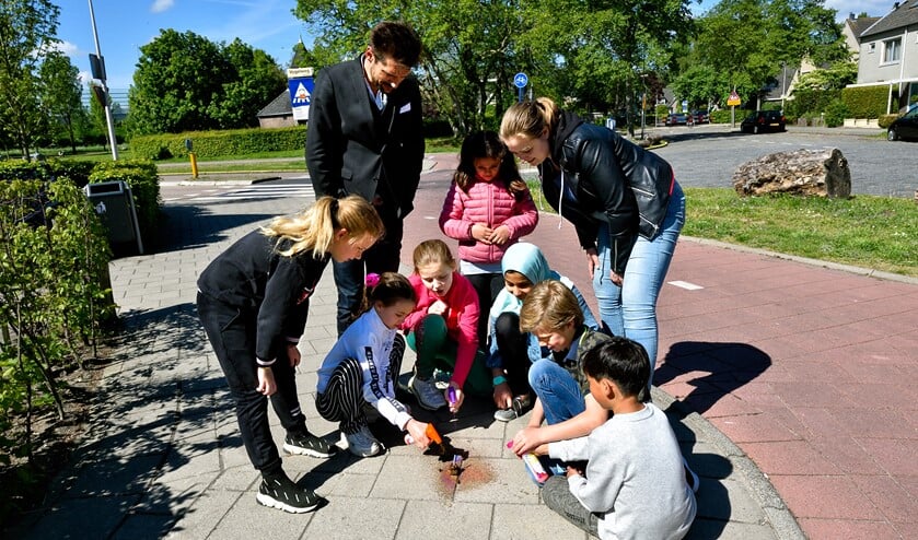 Leerlingen markeren een plek waar hondenpoep ligt.